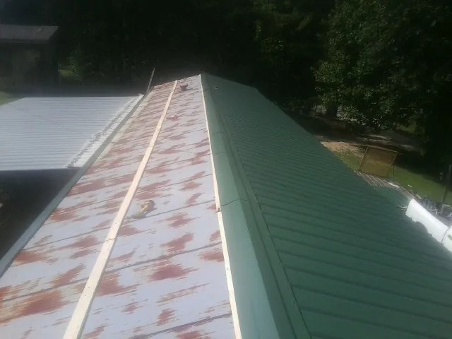Old rusted panels beside newly installed green metal roofing — Wind Damage Roof Repair by Roofing Brothers in Pennington
