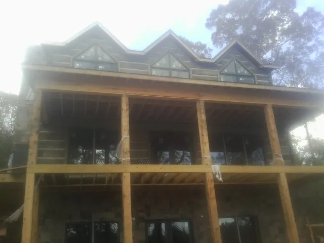 Dormers and porch framing on a large log home under construction — Roof Coating work by our crew in Pennington