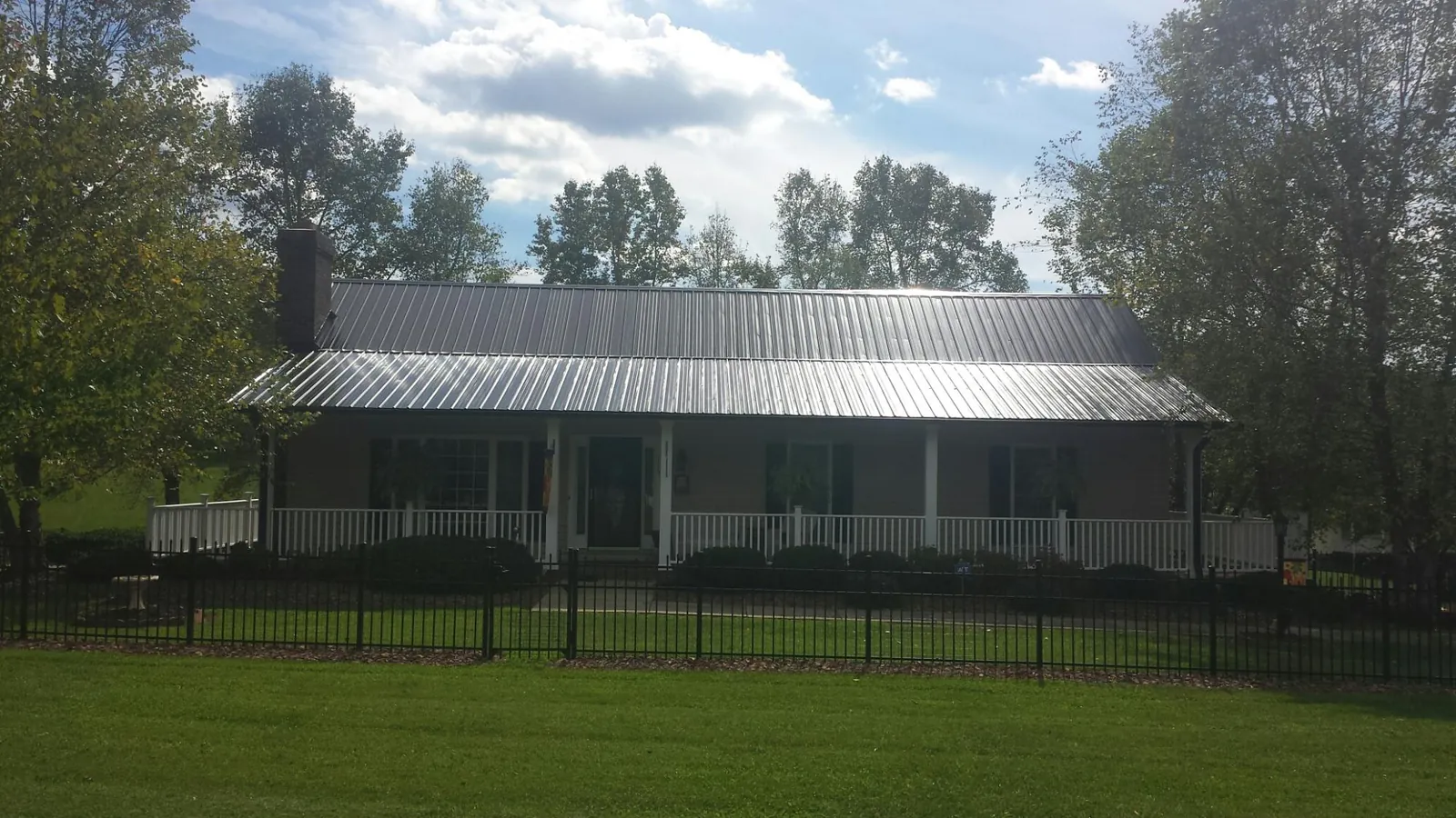 Gray metal roof on a brick ranch with a full width front porch — Gutter Guard Installation work by our crew in Pennington